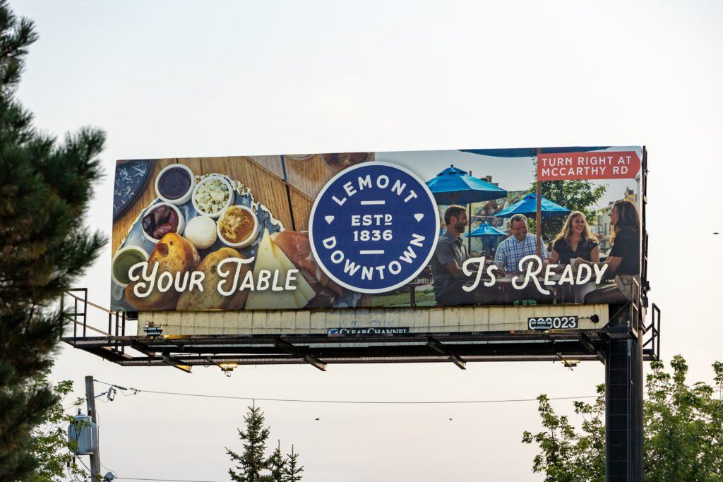 Photo of a billboard showcasing two brand images and a Village Logo advertising Lemont, IL