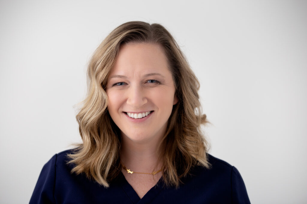 Professional Headshot of a blonde woman smiling with a black blouse and white background