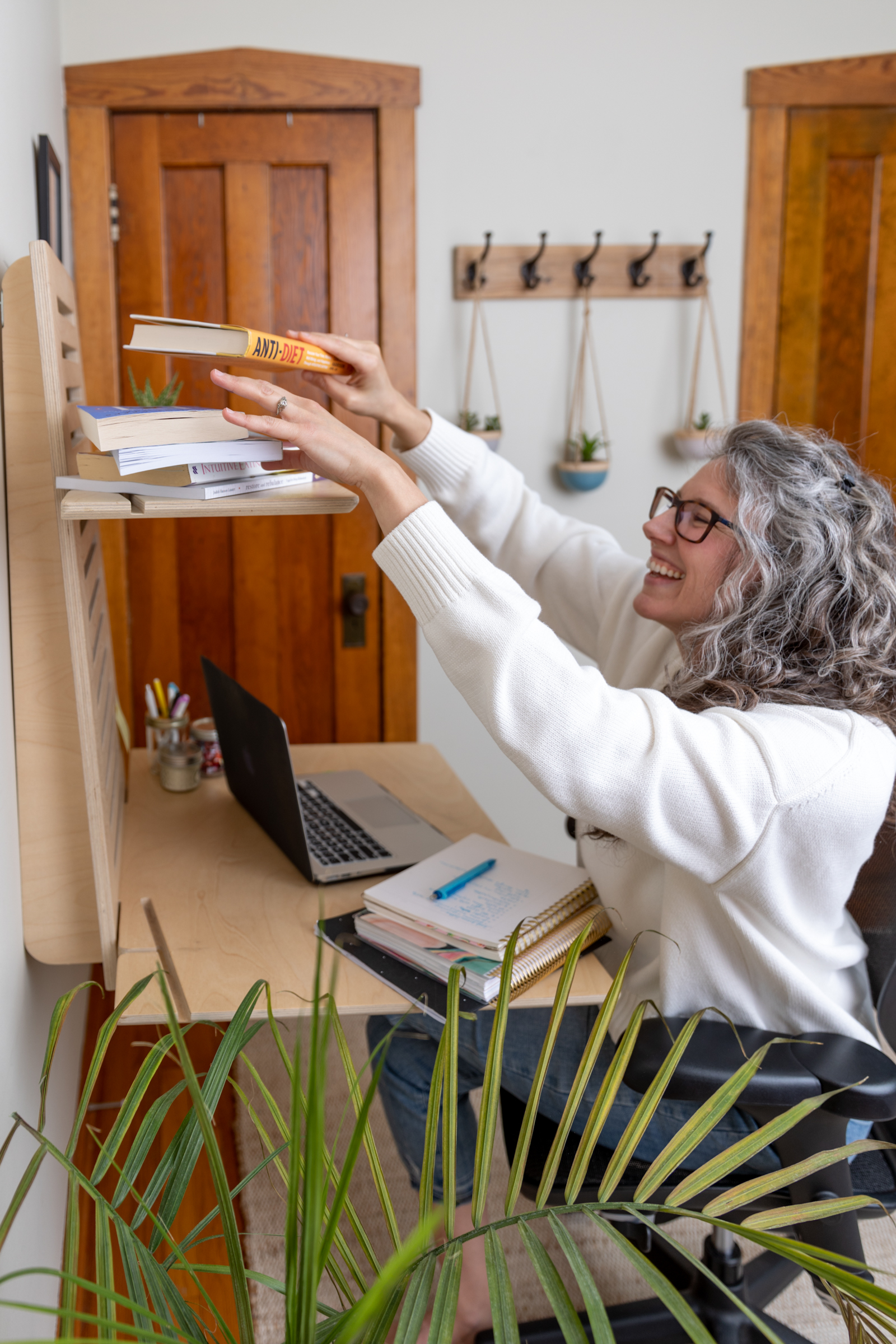 woman sitting at her desk reaching for a book 