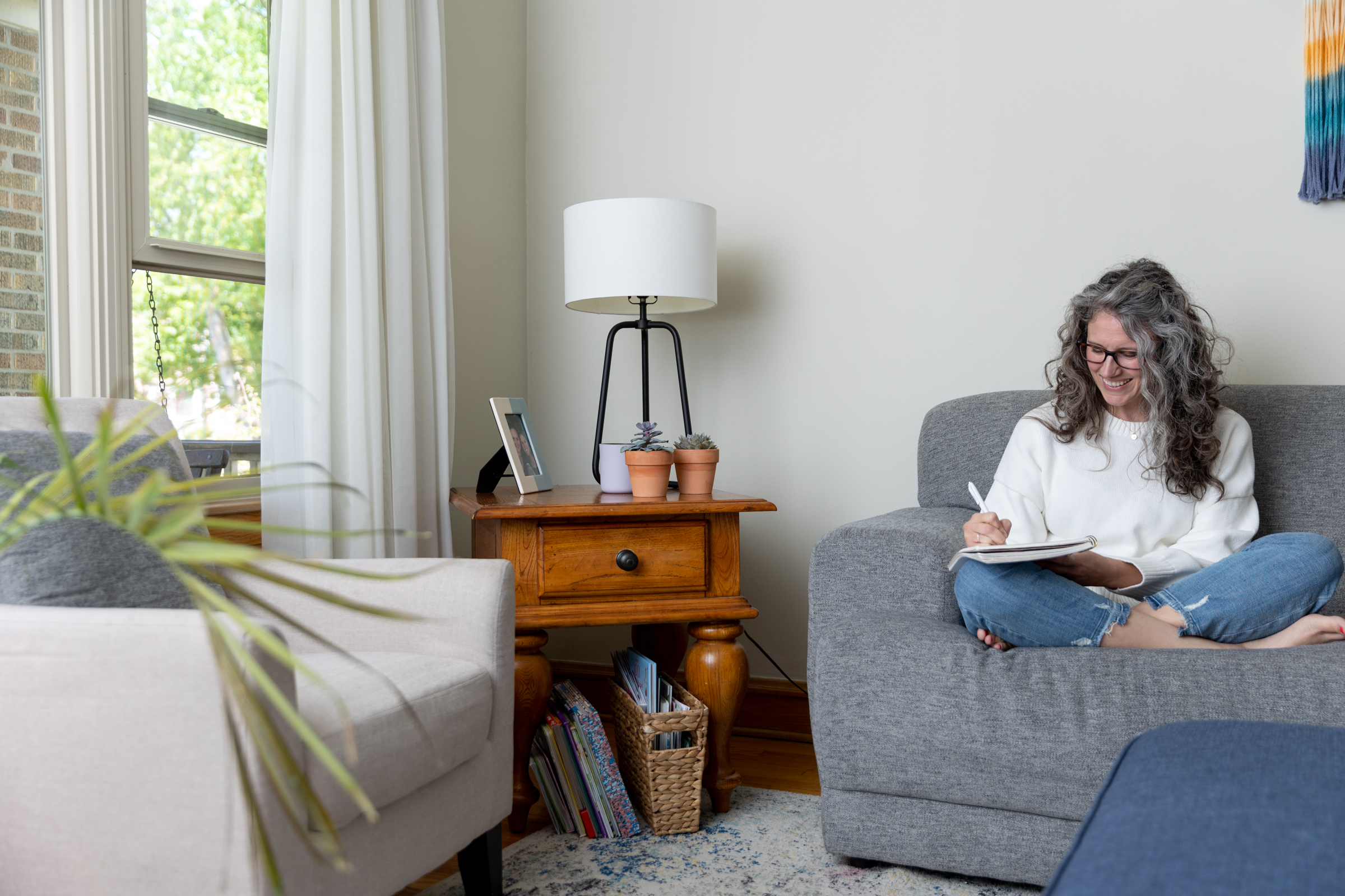 woman sitting on a couch writing in a journal 