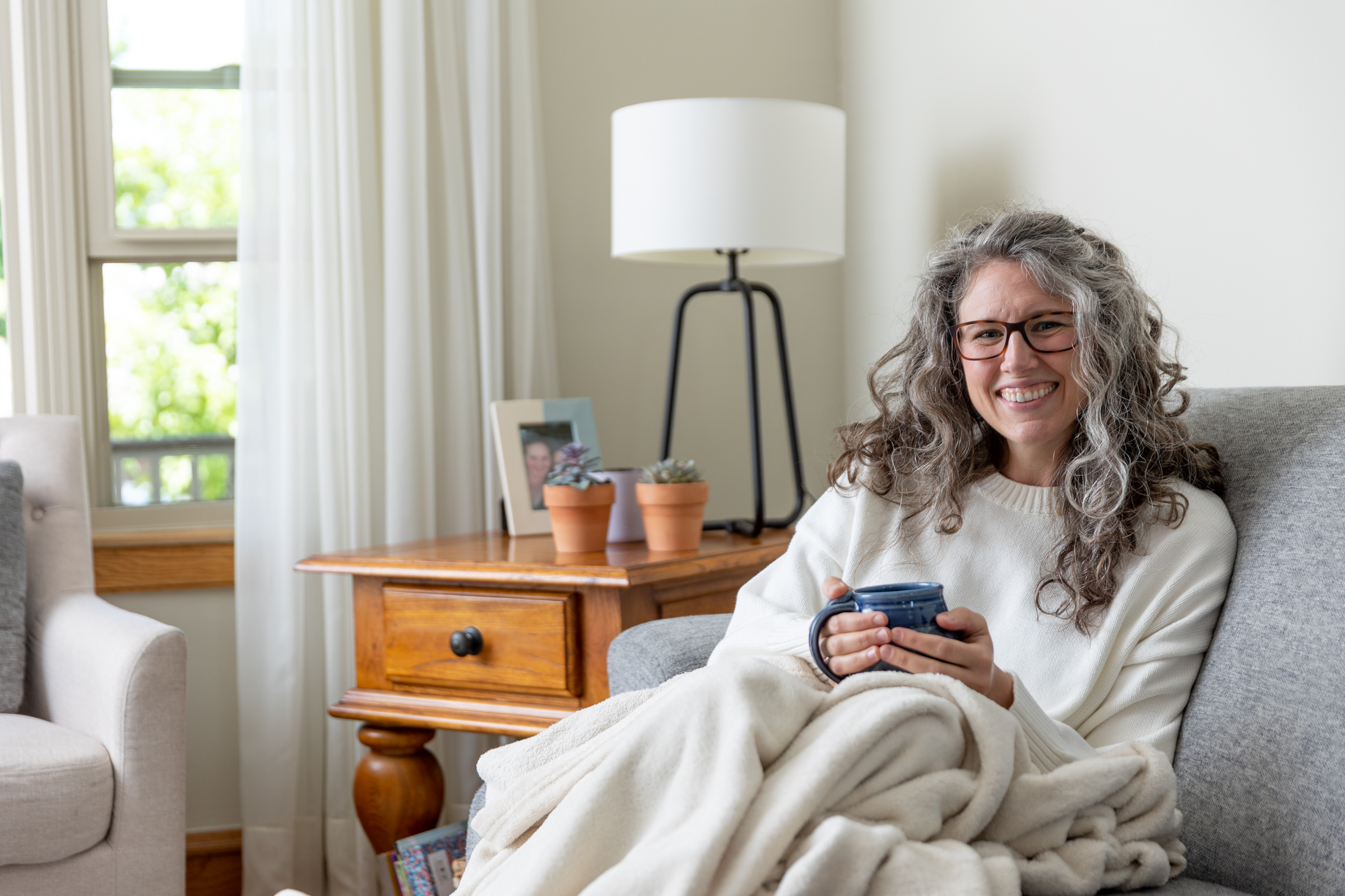 woman sitting on a couch with a mug in her hands 