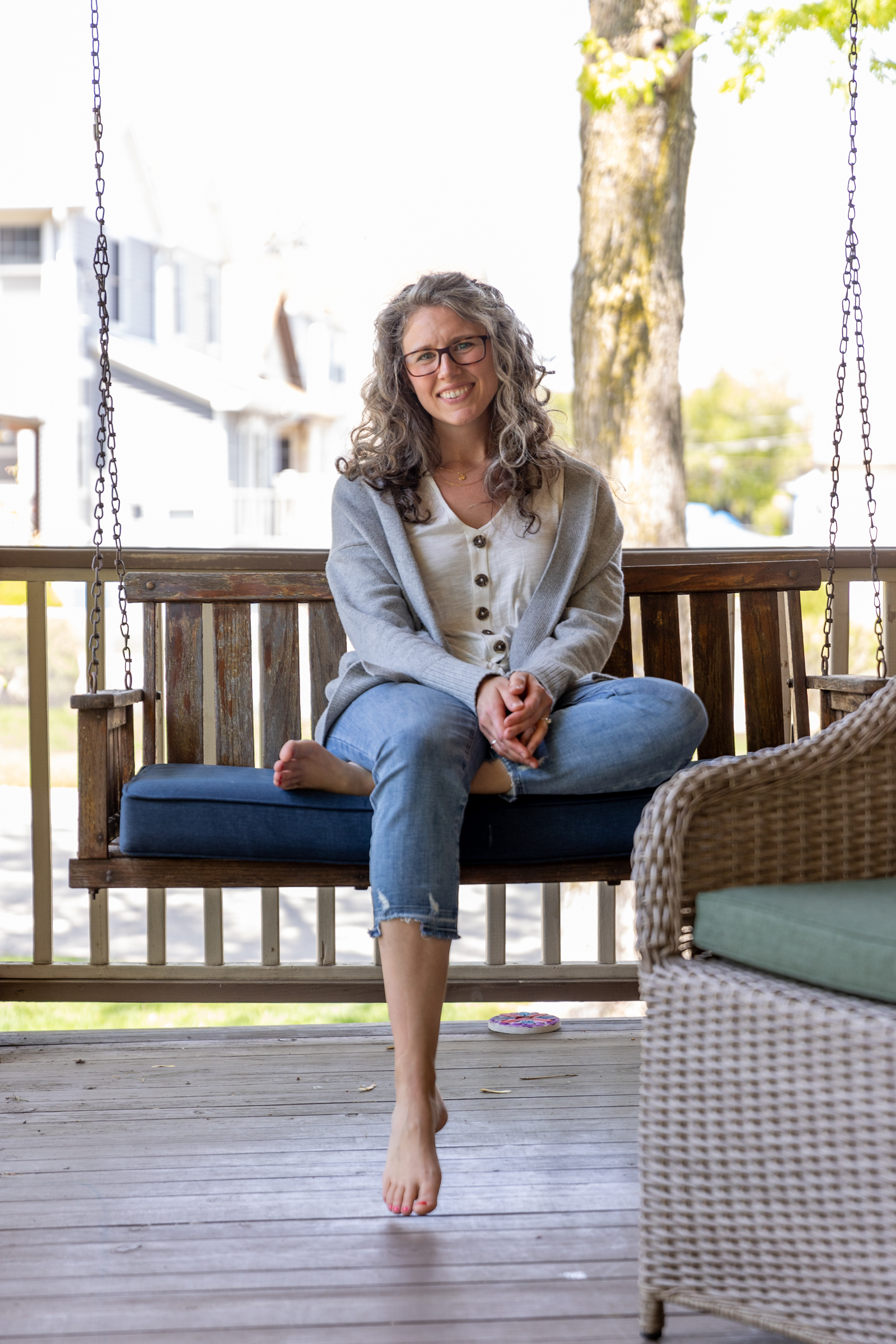 woman sitting on a porch swing barefoot 