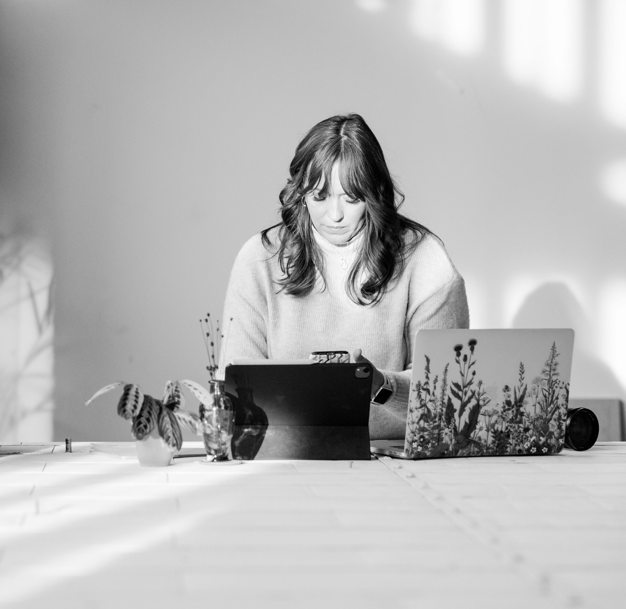 black and white photo ofa female photographer looking at her phone 