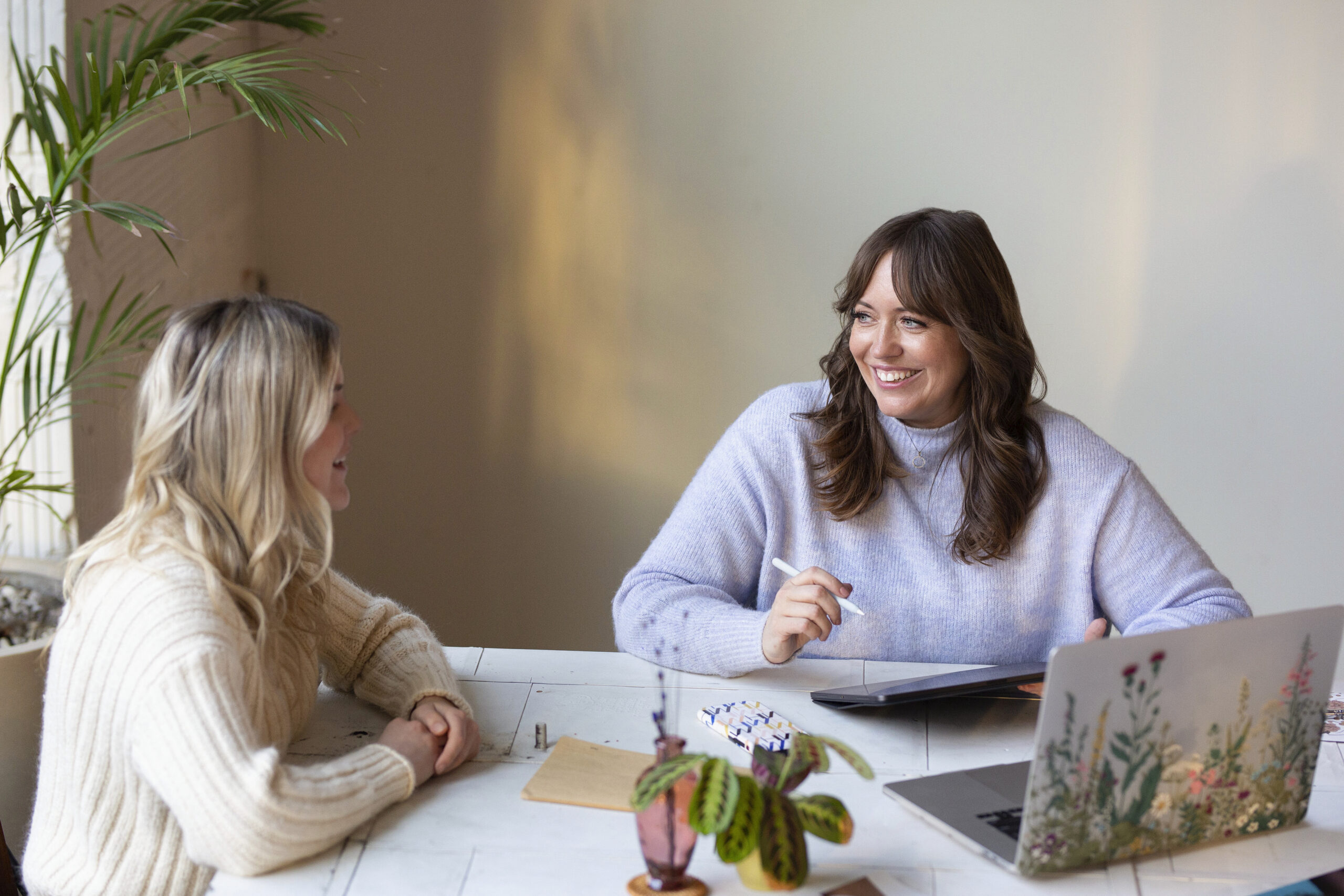 two women talking with each other sitting at a table 