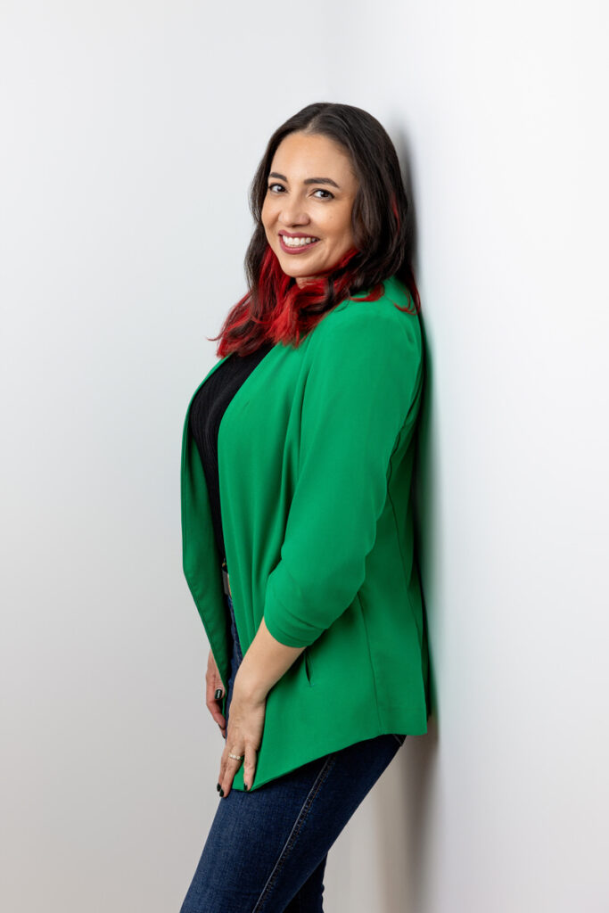 A person in a green blazer leaning against the wall 