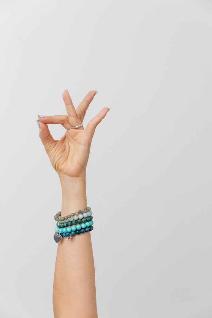 A person wearing blue bracelets makes a hand gesture during a yoga brand session.