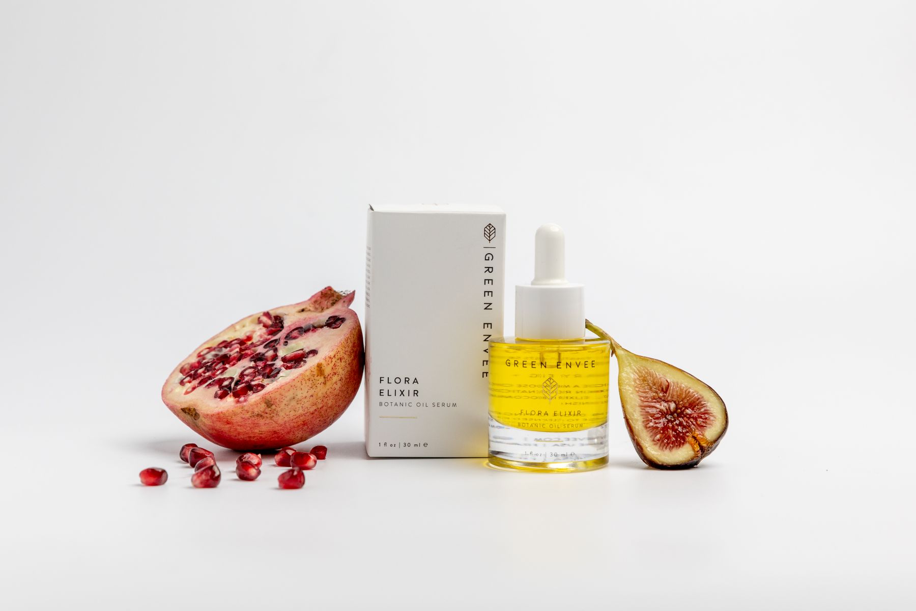 a serum made of pomegranate next to a white box and next to the serum and white box is a pomegranate