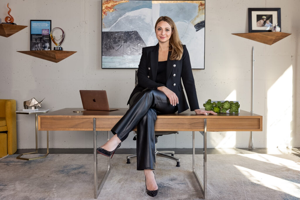 A person sitting on a table in an office with their legs crossed 