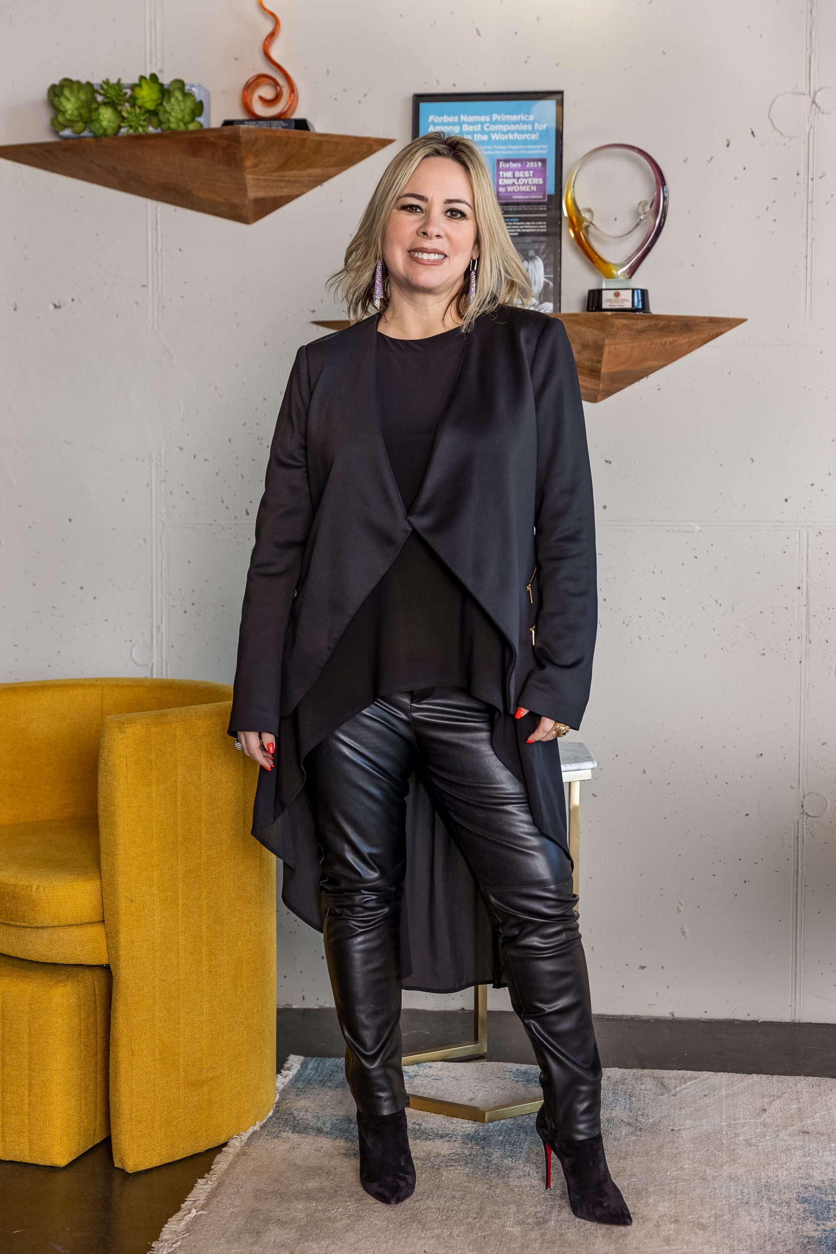 A person in a black outfit standing next to a yellow chair in an office