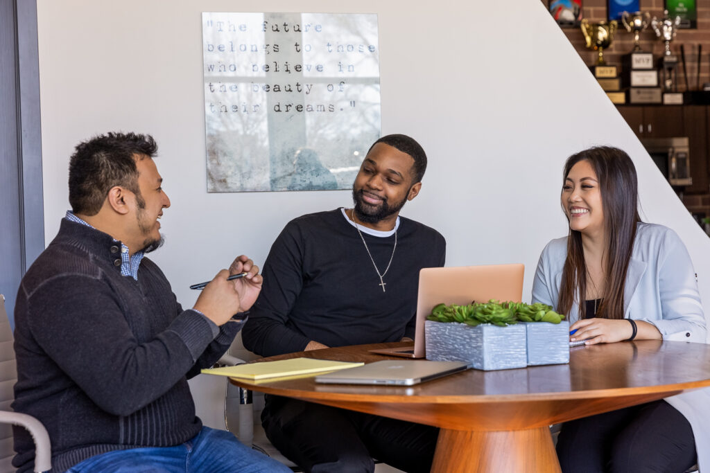 Three people sitting around a table talking and laughing 