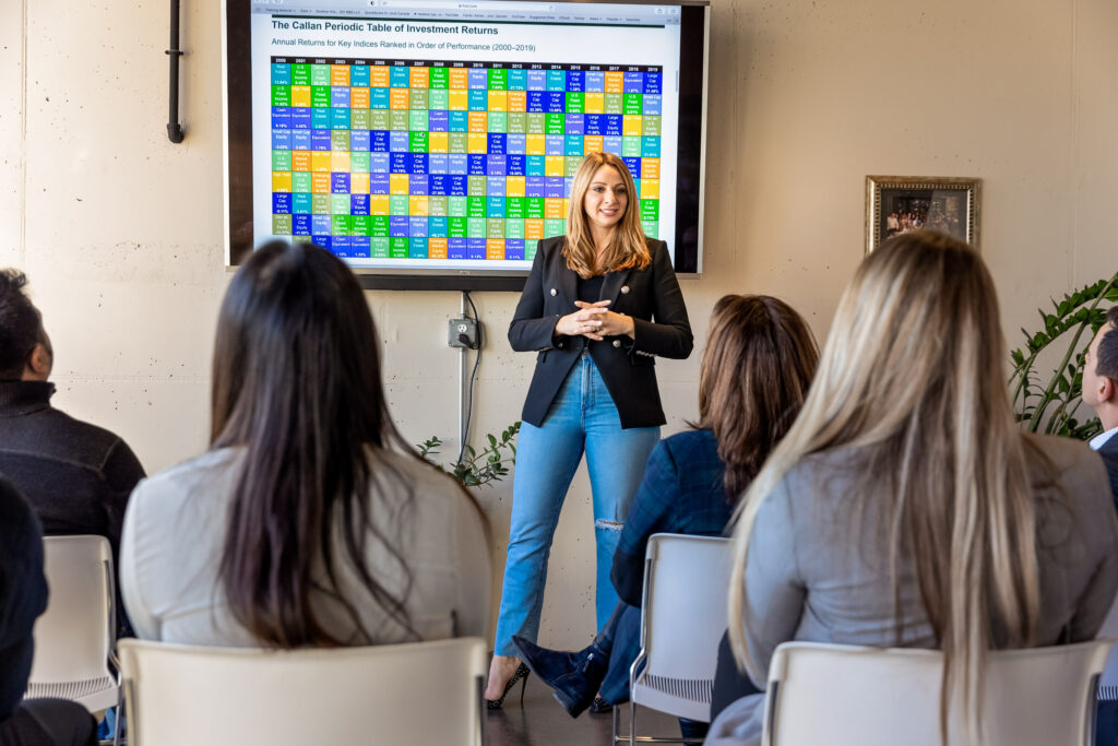 A group of people sitting in a room watching someone give a presentation 