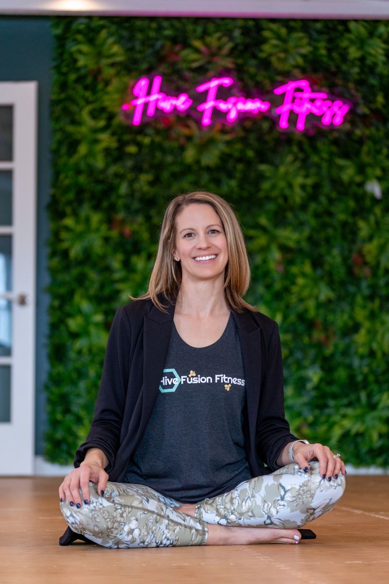 commercial brand photography for hive fusion fitness featuring a woman sitting cross legged on the floor and smiling